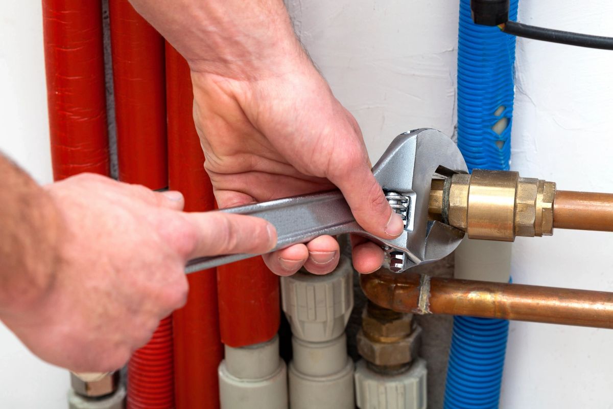 Engineer tightening a brass fitting on copper pipework